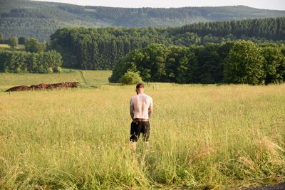 Rear view of shirtless man standing on field