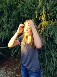 Beautiful young woman standing against plants