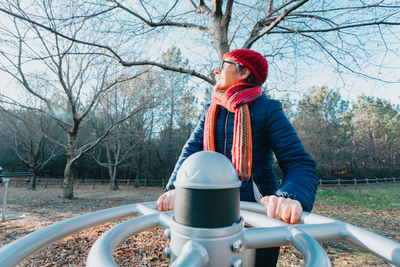 Rear view of woman sitting on railing