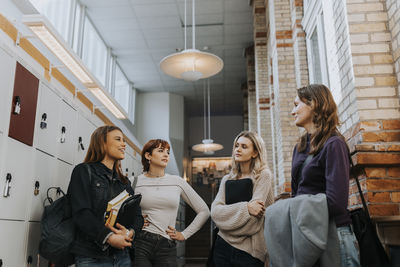 Female students talking while standing in school corridor