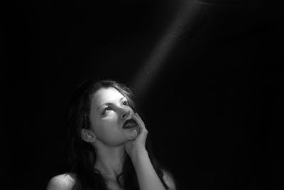 Portrait of a young woman against black background