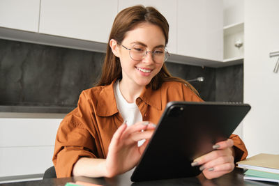 Businesswoman using digital tablet while sitting on table