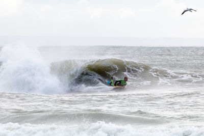 Man surfing in sea against sky