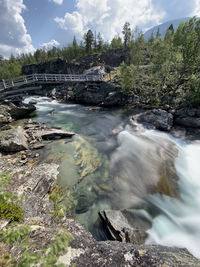 Water flowing through rocks against sky