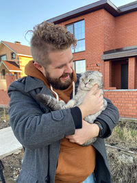 Side view of young woman holding cat