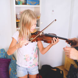 Girl playing with violin while standing at home