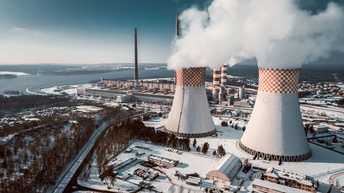 Smoke emitting from factory against sky during winter