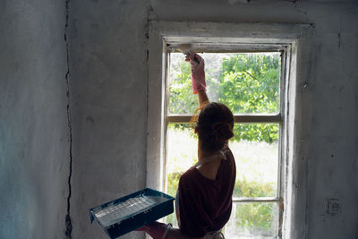 Rear view of woman standing by window