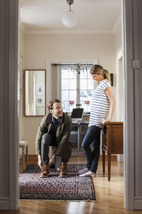 Man wearing shoes while looking at woman in house