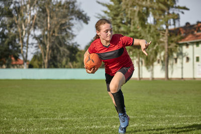 Girl with rugby ball running on sports field