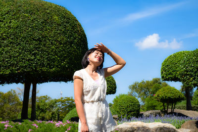 Smiling woman shielding eyes while standing in park