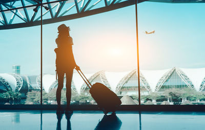 Silhouette woman with luggage standing in airport