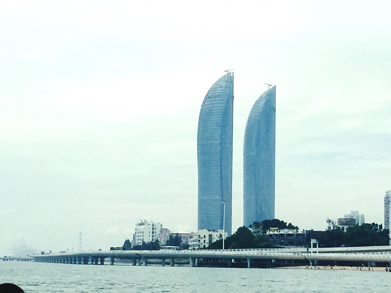 water, waterfront, architecture, built structure, city, river, modern, building exterior, skyscraper, sky, tall - high, sea, outdoors, day, calm, engineering, tranquility, city life, tranquil scene, no people, riverbank, office building