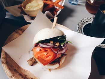 High angle view of burger served with fries and mayonnaise in plate on table indoors