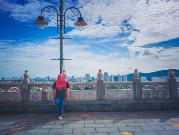 Woman looking down while standing against wall in city