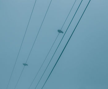 Low angle view of power cables against clear blue sky