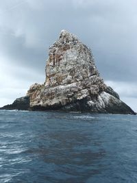 Rock formation by sea against sky