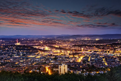 Aerial view of illuminated cityscape against sky at sunset