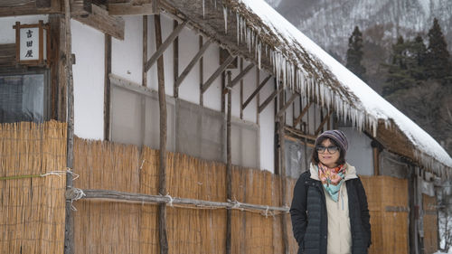 Portrait of young woman standing against building