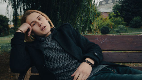 Full length of young woman sitting on bench in park