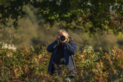 Senior man photographing against trees