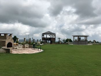 Built structure on grassy field against cloudy sky