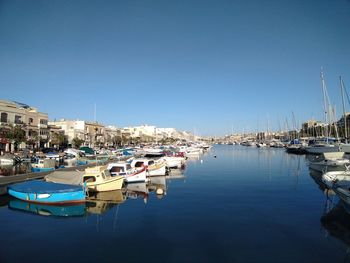Boats moored at harbor against clear sky