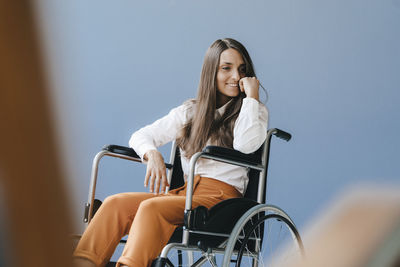 Young handicapped woman sitting in wheelchair, smiling