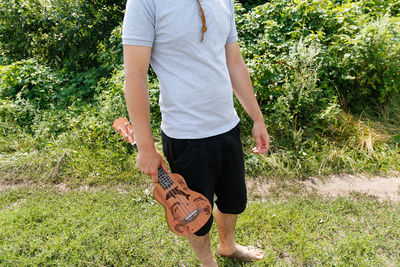 Music hobby. young beautiful caucasian man holding ukulele outside. handsome hipster guy plays