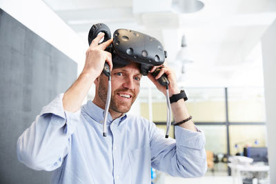 Smiling businessman wearing virtual reality stimulator at creative office