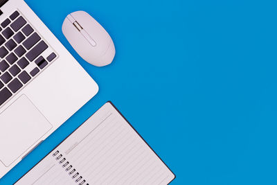 Close-up of laptop on table against blue sky