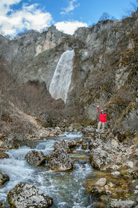 Full length of woman standing against waterfall