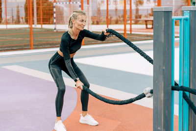 A woman trains on battle ropes on the sports ground.