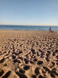 Surface level of sand on beach against clear sky