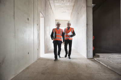 Two men wearing safety walking in building under construction