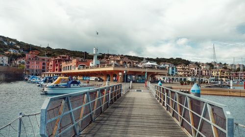 Pier over sea against sky in city