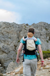 Rear view of friends walking on rock against sky