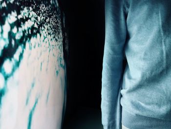 Close-up of man standing against dark wall