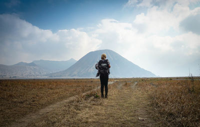 Rear view of woman standing on land against sky