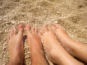 Low section of couple on sand at beach