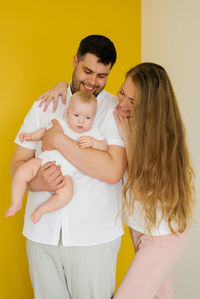 Smiling young happy parents, mom dad with baby baby son looking at the camera. family day 