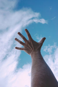 Low angle view of human hand against sky