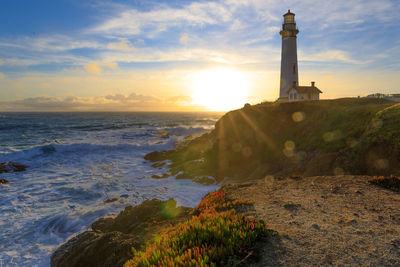 Lighthouse by sea against sky