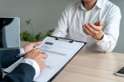 Midsection of man using mobile phone on table