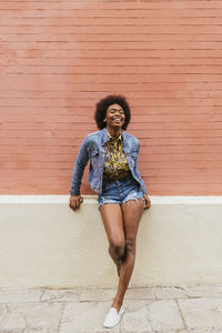 Happy mid adult woman leaning on wall