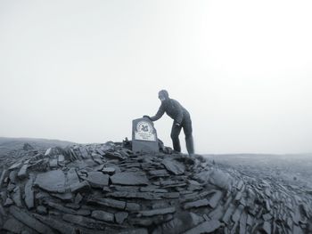 Men standing on rock against sky