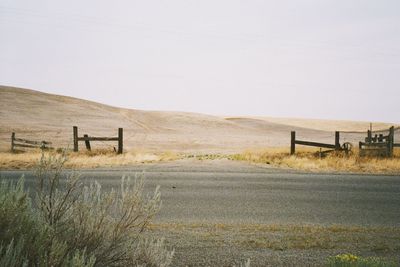 Scenic view of road amidst field against sky