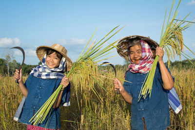 Senior farmer standing with granddaughter on field