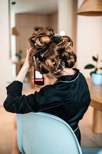 Rear view of woman sitting at home