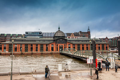 People on bridge over canal in city